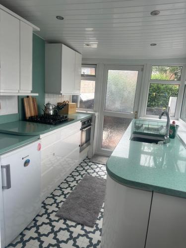 cocina con armarios blancos y encimera verde en Family house, en Oldham