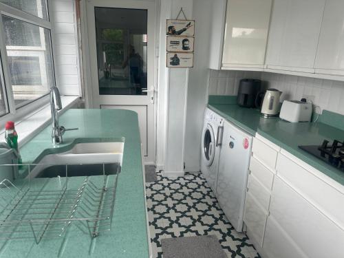 a kitchen with a sink and a washing machine at Family house in Oldham