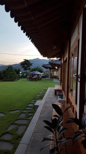a porch of a building with a green field at Suncheon Sagyejeol Haeoreum Hanok Pension in Suncheon