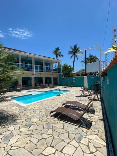 a swimming pool with lounge chairs and a building at Pousada Fast Inn in Guarujá