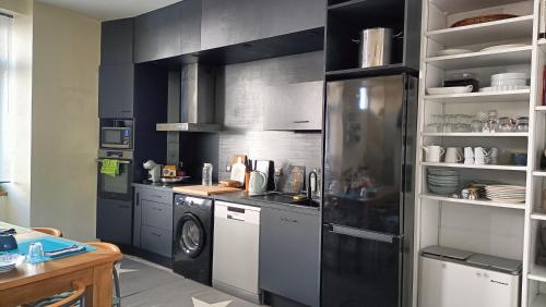 サン・ブリューにあるChambre maison de ville dans la cité des trois valléesのキッチン(黒いキャビネット、洗濯機付)