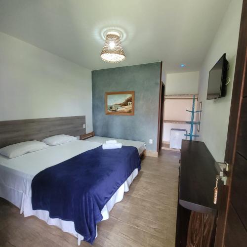 a bedroom with a large bed and a television at Pousada Aconchego de Genipabu in Jenipabu