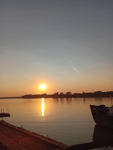 a sunset on a river with a boat in the water at Felikitas in Smederevo