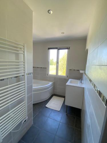 La salle de bains blanche est pourvue d'une baignoire, d'un lavabo et d'une baignoire. dans l'établissement La ville es goutté, à Créhen