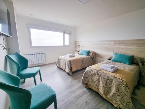 a bedroom with two beds and a chair and a window at Edificio Brown in Caleta Olivia