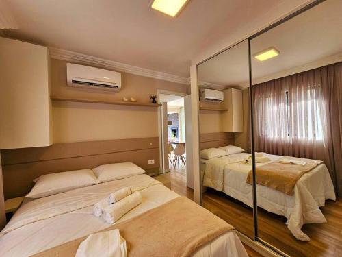 a hotel room with two beds and a mirror at Ap Moderno Ap 21 Soho Life in Curitiba