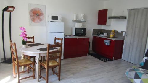 une cuisine avec une table avec des chaises et un réfrigérateur dans l'établissement Les Cactus, à Bagnères-de-Bigorre