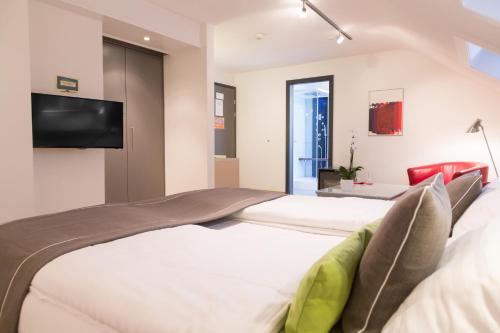 a bedroom with two beds and a flat screen tv at Hôtel Des Arts in Neuchâtel