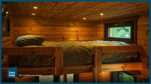 a bed in a log cabin with a window at Two Tiny Houses in Agarcia