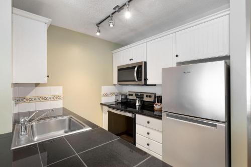 a kitchen with white cabinets and a stainless steel refrigerator at The Aspens by Whiski Jack in Whistler