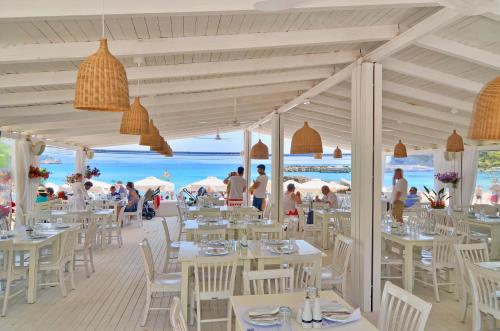 un restaurante en la playa con mesas y sillas blancas en Cape North West, en Parga