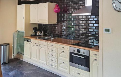 a kitchen with white cabinets and a brick wall at Huize Roland in Sint Annaland