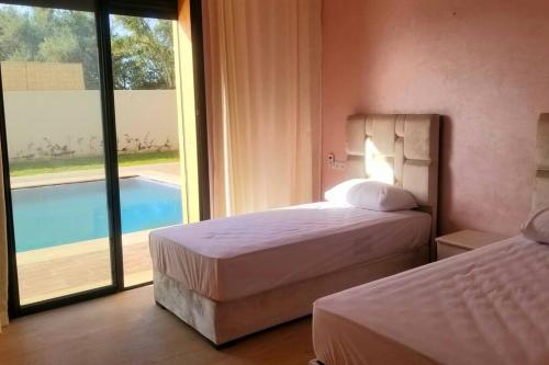 a bedroom with two beds and a view of a pool at Villa Familiale in Marrakech