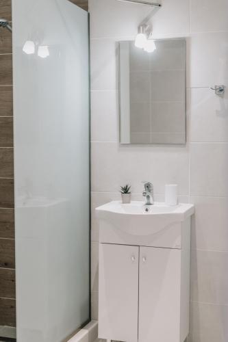 a white bathroom with a sink and a mirror at Sea Sailing Apartments in Kontokali