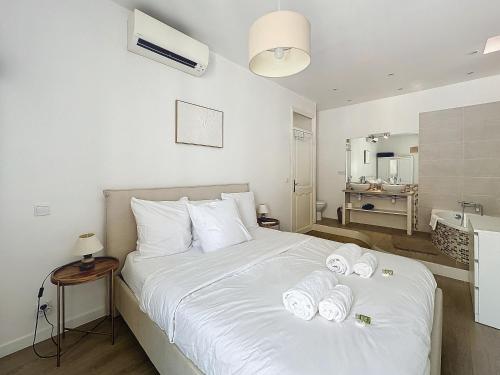 une chambre avec un lit blanc avec des serviettes dessus dans l'établissement 64m2 face Majestic - 50m palais & plages, à Cannes