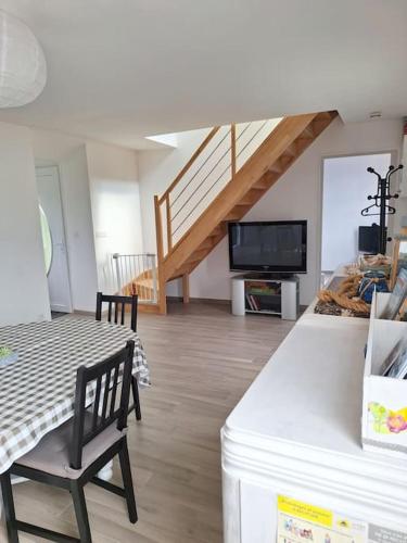 un salon avec une table et une télévision dans l'établissement La petite maison proche du Mont Saint Michel, à Pontorson