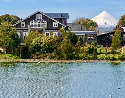 a house next to a lake with a mountain in the background at Hotel Boutique Casa Werner in Puerto Varas
