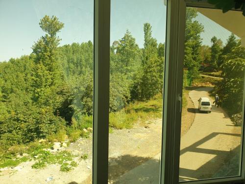 a window with a view of a car parked on a road at Mashal Palace Apartment's in Nathia Gali