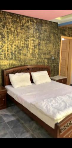 a bedroom with a bed with a wooden headboard at Mashal Palace Apartment's in Nathia Gali