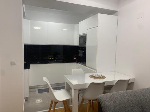 a white kitchen with a white table and chairs at C&E Apartment in Struga