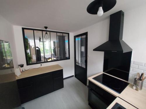 - une cuisine avec des placards noirs, un évier et une cuisinière dans l'établissement Cinéma room 2 chambres séparées, à Morlaix