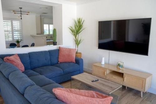 a living room with a blue couch and a tv at The Pink Cactus - Desert Retreat - Luxe Pool, Golf & Game Room in Indio