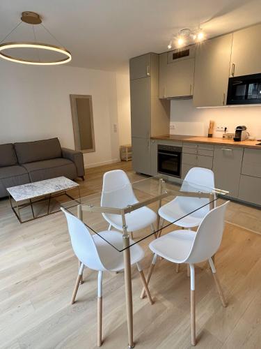 a living room with a glass table and white chairs at Nice flat Paris Clichy in Clichy