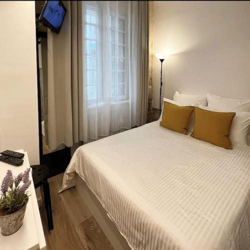 - une chambre avec un grand lit blanc et des oreillers jaunes dans l'établissement Cozy studio in Saint Germain dès près, à Paris