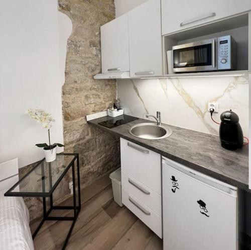 une petite cuisine avec un évier et un micro-ondes dans l'établissement Cozy studio in Saint Germain dès près, à Paris