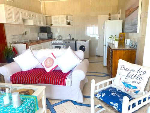un salon avec un canapé blanc et une cuisine dans l'établissement Heenalu surf camp, à Tamraght Ouzdar