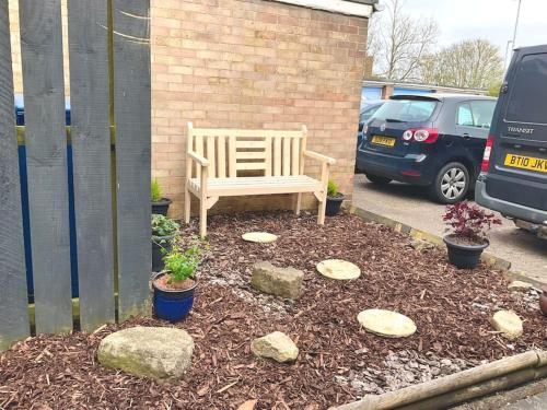a wooden bench sitting in a yard with rocks at Morpeth Apartment in Morpeth