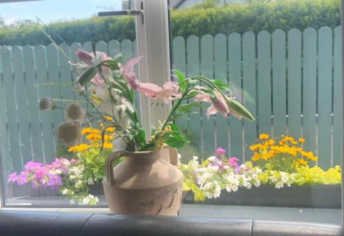 a vase filled with flowers sitting on a window sill at Swallow's Rest Garden Apartment in Ashbourne