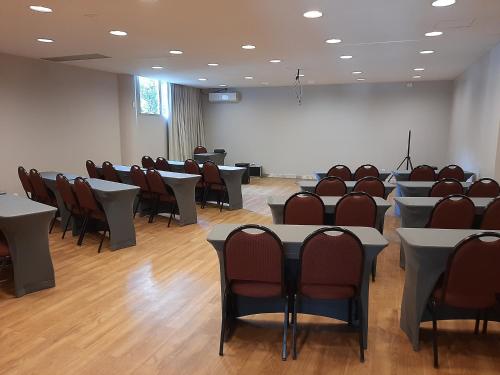 a conference room with tables and chairs and a screen at eSuites Lagoa Santa in Lagoa Santa