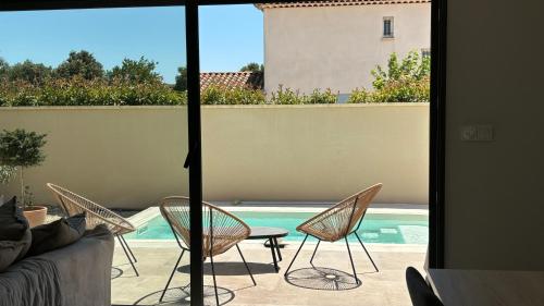 une terrasse avec des chaises, une table et une piscine dans l'établissement Maison neuve climatisée Piscine 4 personnes, à Pernes-les-Fontaines
