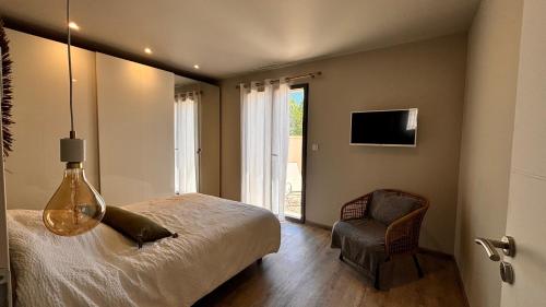 une chambre avec un lit, une chaise et une télévision dans l'établissement Maison neuve climatisée Piscine 4 personnes, à Pernes-les-Fontaines