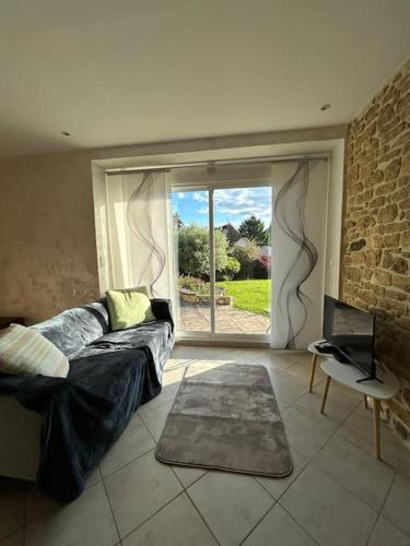 un salon avec un canapé et une grande fenêtre dans l'établissement Un havre de paix au Périgord, à Anlhiac