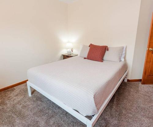 a bedroom with a white bed with a red pillow at Kinston Getaway #2 in Kinston