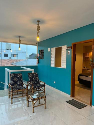 a living room with two chairs and a blue wall at Pousada Fast Inn in Guarujá