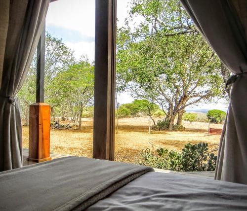 a bedroom with a view of a field from a window at Chumbi Bush House in Hluhluwe