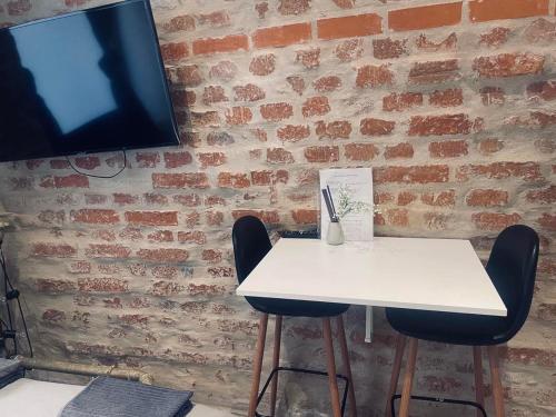 a white table with two chairs and a tv on a brick wall at Travel box no window studio 2 now with AC in Stockholm