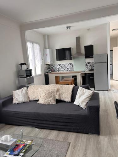 un salon avec un canapé noir et une cuisine dans l'établissement Appartement T3 de 54 m2 Saint Esprit Bayonne, à Bayonne