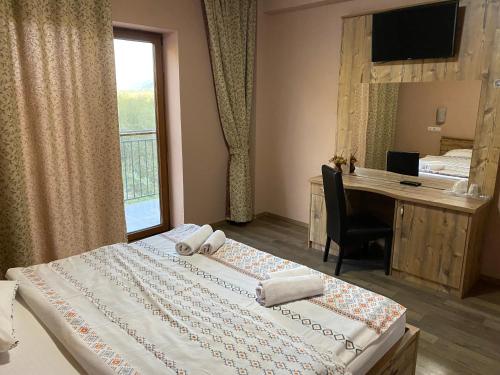 a bedroom with two beds and a desk and a window at Pensiune Marginimea Sibiului in Orlat