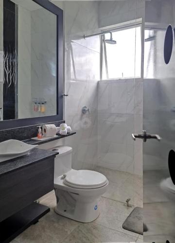 a bathroom with a toilet and a glass shower at HOTEL BOUTIQUE KRYSTAL in Quito