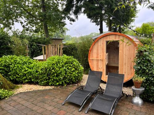 two black chairs sitting in front of a wooden shed at Het Verwende Nest met privé hottub & Barrel sauna in Voorthuizen