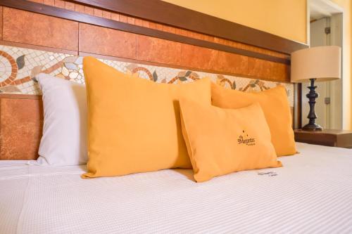 a bed with orange pillows and a wooden headboard at Villa las Margaritas Plaza Cristal in Xalapa