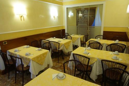 a restaurant with tables and chairs with yellow table cloth at Hotel Miami in Rome