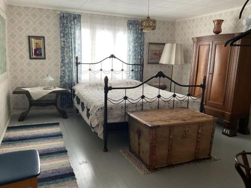a bedroom with a bed with a wooden trunk in it at Perinteinen maalaistalo in Vesivehmaa