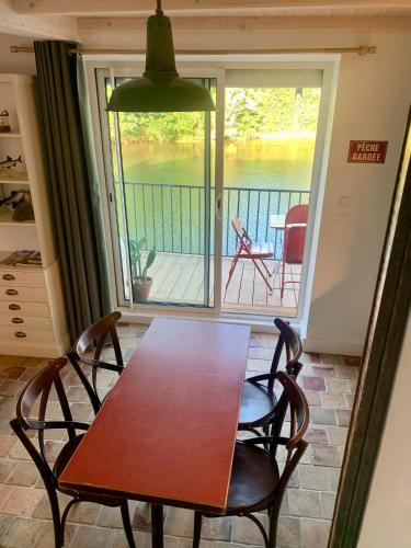 a table and chairs in a room with a balcony at La Maison du Pêcheur in Verdun-sur-le-Doubs