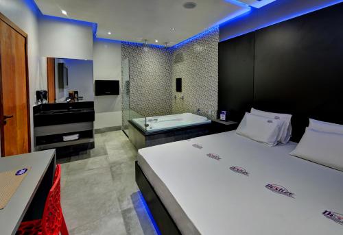 a bedroom with a large bed and a bath tub at Deslize Motel 2 in Uberlândia