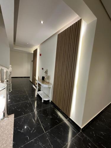 a hallway with a black tile floor and white walls at تاج الملقي للشقق المخدومة in Hail